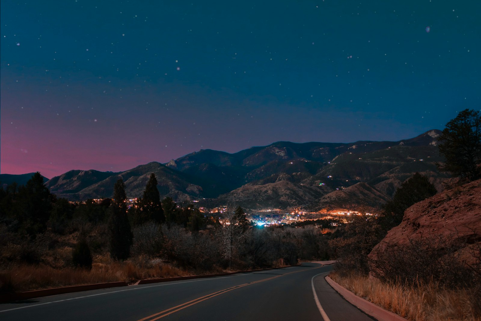Night mountain road winding through switchbacks under a starry dusk sky